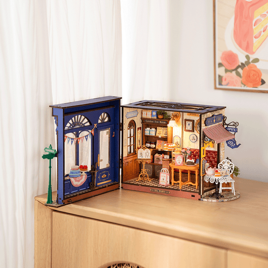 Open toy store model inside a wooden box on a table with a floral painting in the background.